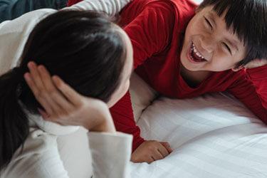 Mum and son lying down and laughing as they socialise together