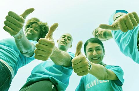 Four Volunteer's smiling and giving the thumbs up