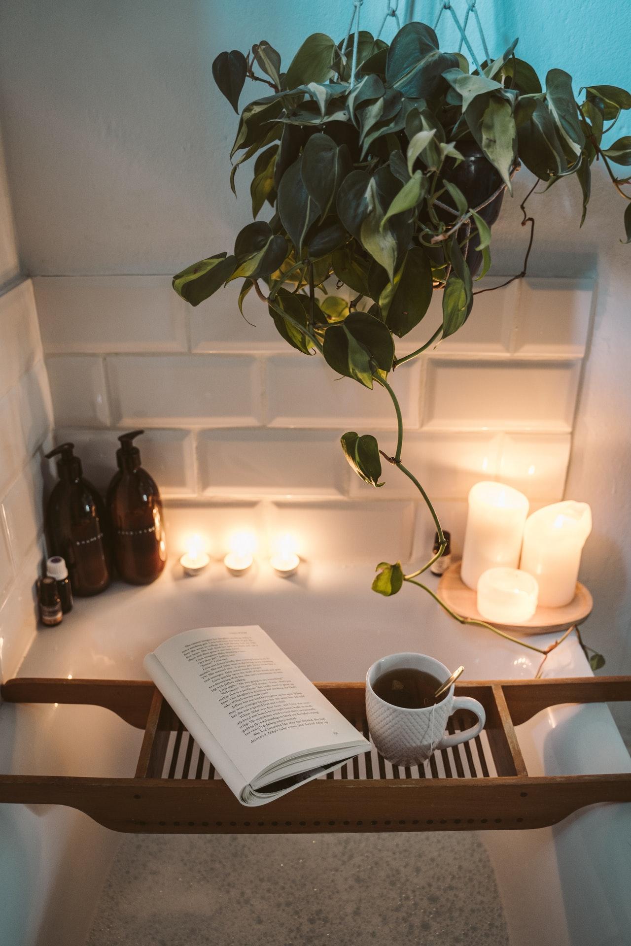 Book, coffee and candles over and around a bath in preparation for a wash