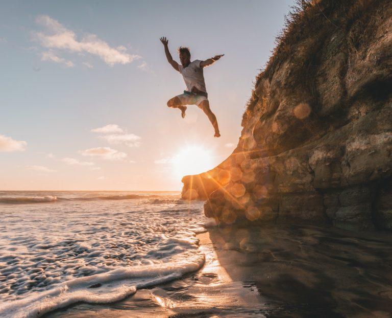 A man jumping from a cliff into the sea for fun while on holiday