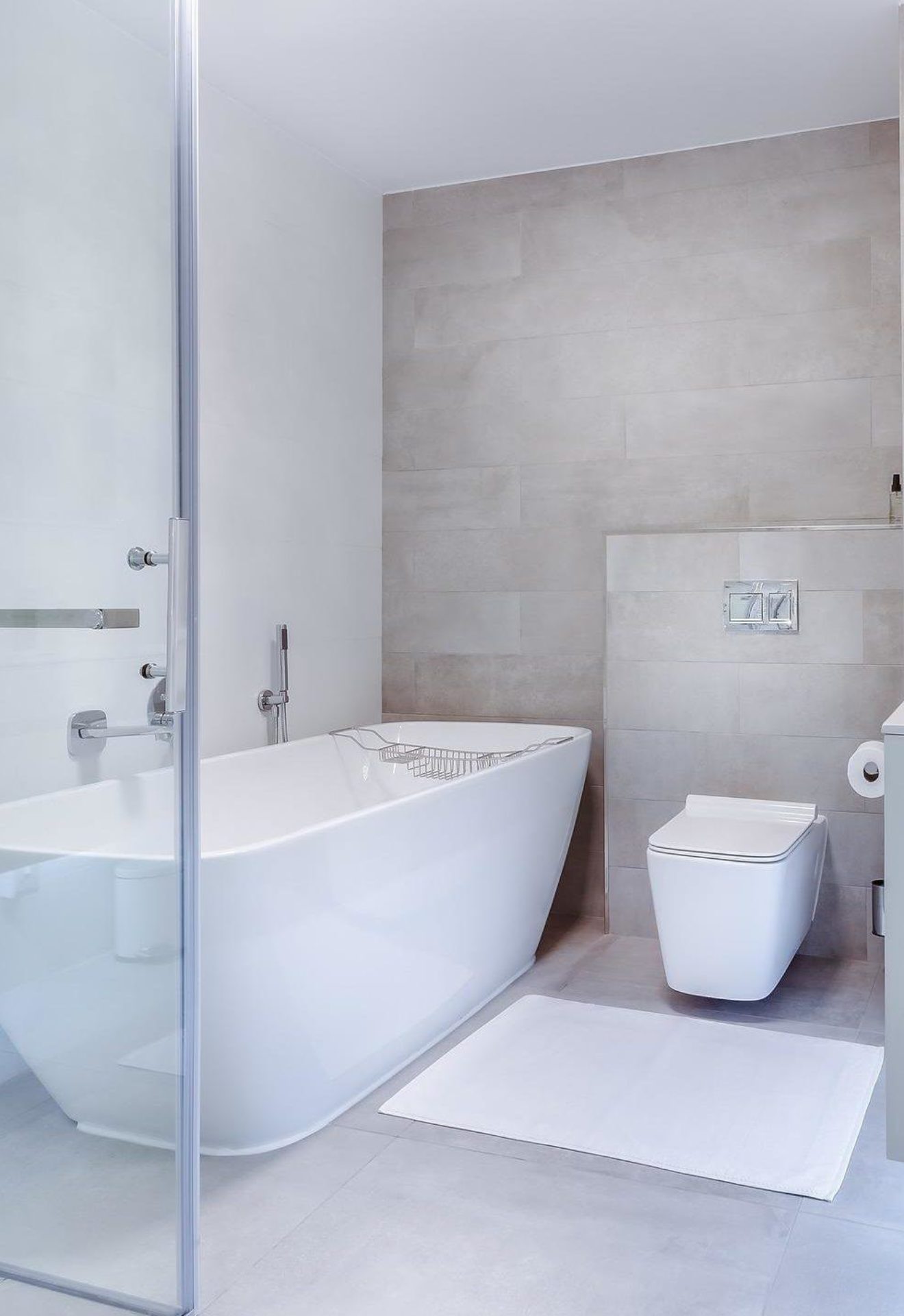 White bathroom with a white bath mat in the middle of the floor