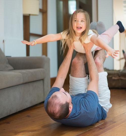 Man Lying on the Floor While Lifting a Girl who is doing superman while lying on man's outstretched knees to feet