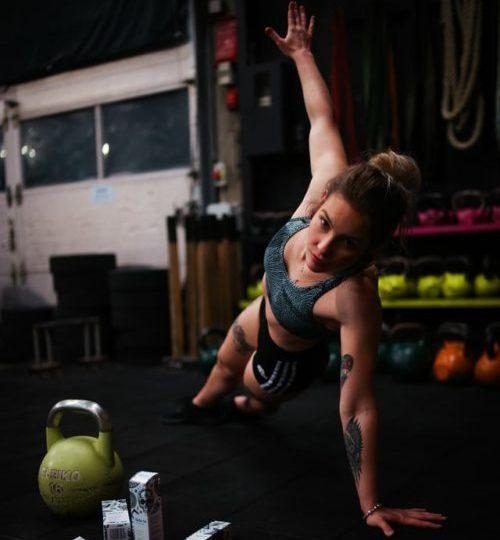 Woman doing a side press-up in the gym surrounded by weights