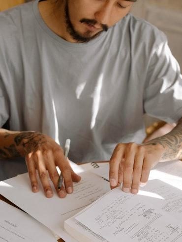 A man sitting and taking notes as he learns, boosting his well-being as he experiences Flow