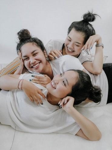 Three friends smiling as they relax and Socialise together, boosting their well-being through laughter