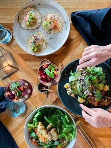 Birds eye view of two people eating from a selection of plates of healthy food that they know will nourish them and boost their well-being