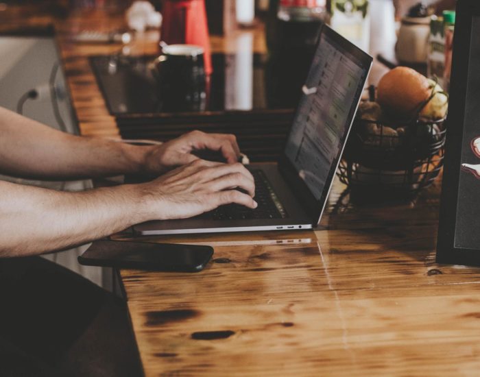 Person In Front Of Laptop On Brown Wooden Table